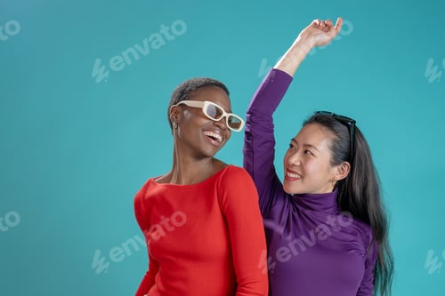 Preview: Two happy women pose on blue studio background