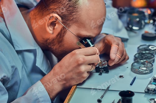 Preview: Expirienced clockmaster is fixing old watch for a customer at his repairing workshop