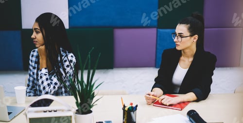 Preview: Serious multiethnic female colleagues during meeting in office