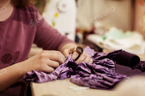 Preview: Female hands sewing cloth with needle at seamstress workplace.