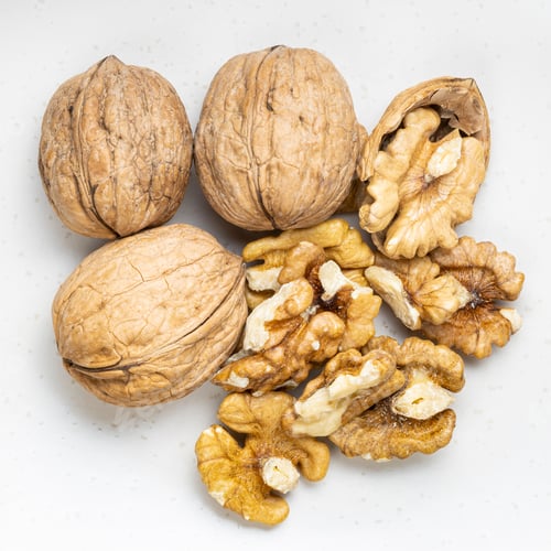 Preview: several peeled and whole walnuts close up on gray