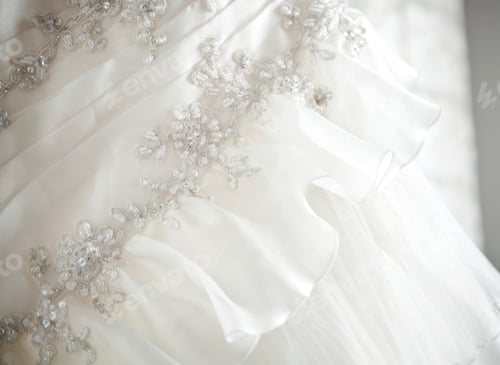 Preview: Close up of elegant white wedding dress with floral embroidery and ruffles