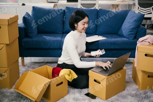 Preview: Asian woman managing sme business, checking orders and inventory online from home