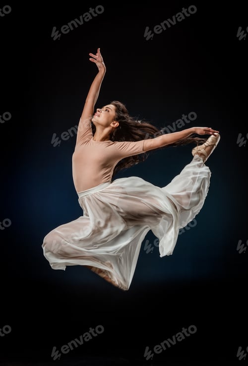Preview: young ballerina in elegant clothing jumping on dark backdrop