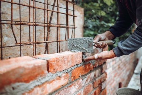 Preview: Professional worker using pan knife for building brick walls with cement and mortar