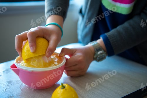 Preview: Girl using lemon juicer in the kitchen