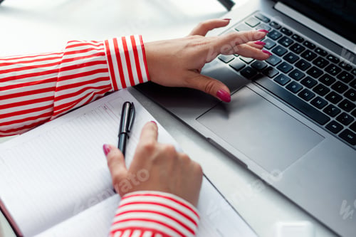Preview: Close-up of the hands of a businesswoman typing on a laptop at a table in a cafe.