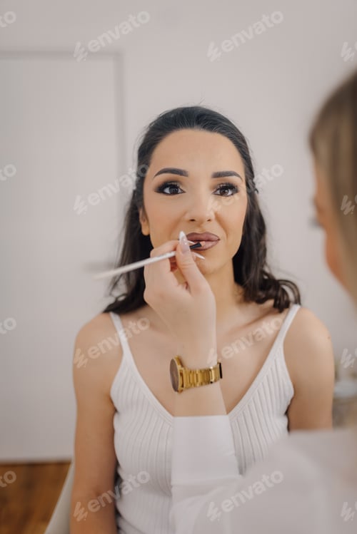 Preview: Makeup artist applying lipstick on client's lips in beauty salon