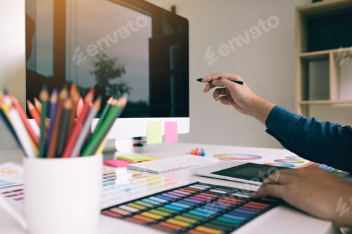 Preview: Graphic designer holding pen pointing computer at workplace.