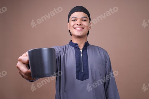 Preview: Young Muslim Male Drink A Glass Of Water Breakfasting At Iftar Time On Beige Studio Wall