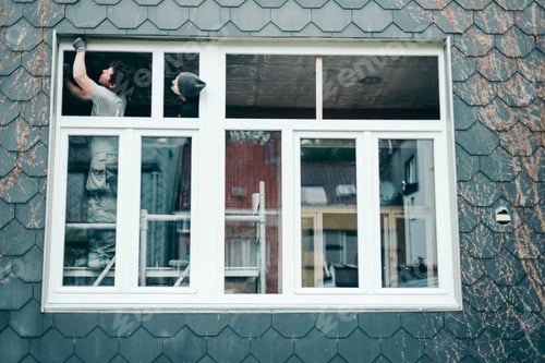 Preview: Two men are repairing a plastic window.