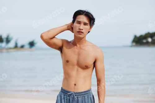 Preview: Smiling Asian Man Enjoying Tropical Beach Vacation: Muscular Torso on the Sand and Palm Trees in