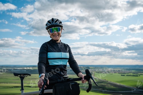 Preview: Young woman cyclist enjoying scenic view from gravel bike on hilltop