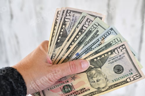 Preview: A female holds a handful of money, currency, cash, salary, extra income, side hustle, earnings