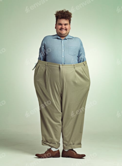 Preview: Diet progress. Shot of an overweight man wearing a pair of oversized pants looking pleased.