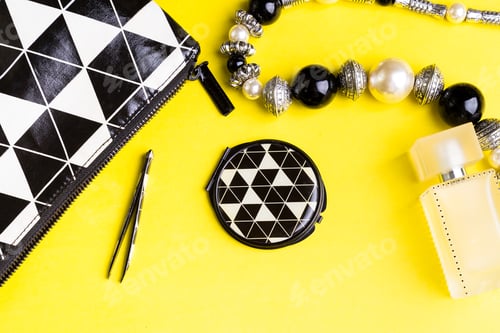 Preview: Woman handbag with makeup and accessories on yellow background. Flat lay.