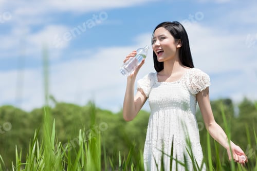 Preview: Young woman drinking water outdoors