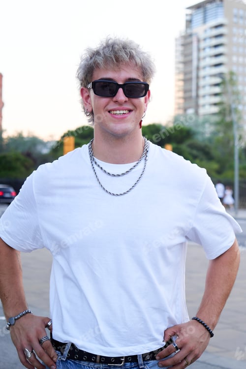 Preview: Portrait of a caucasian young man looking at camera smiling, standing in urban street.
