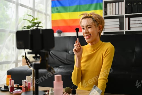 Preview: Charming young gay man blogger recording make up tutorial, live streaming at home.