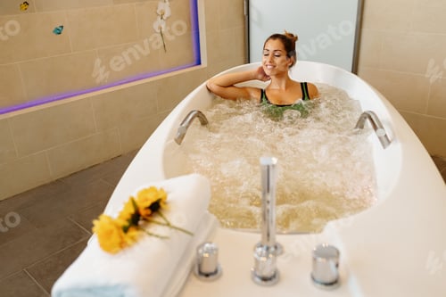 Preview: Young beautiful woman enjoying in hydromassage during spa treatment.