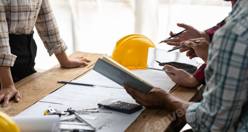 Preview: Brainstorming group of architects and engineers discuss building blueprint design paperwork.