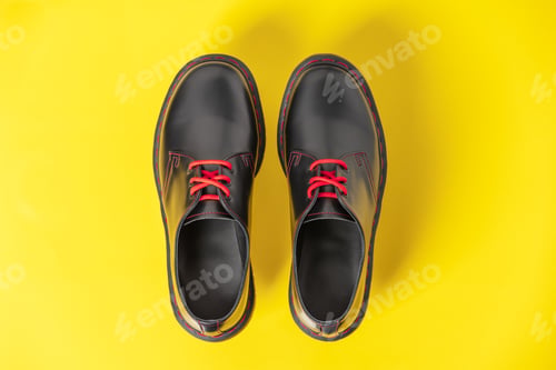 Preview: Stylish black leather shoes on yellow background, flat lay, top view