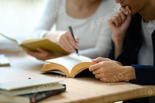 Preview: Close up of university students working together on academic project in a modern study space