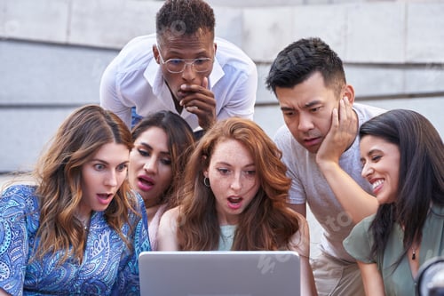 Preview: Group of multi-ethnic people look at laptop screen with a shocked expression on their faces.
