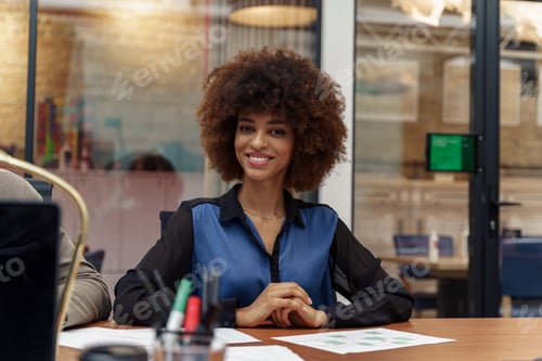 Preview: Smiling african businesswoman sitting on his workplace in modern office