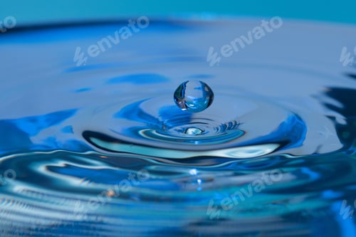 Preview: Amazing shot of a droplet bouncing on water - blue background