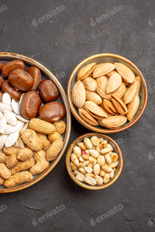 Preview: top view nut composition peanuts and other nuts on grey background many walnut nut