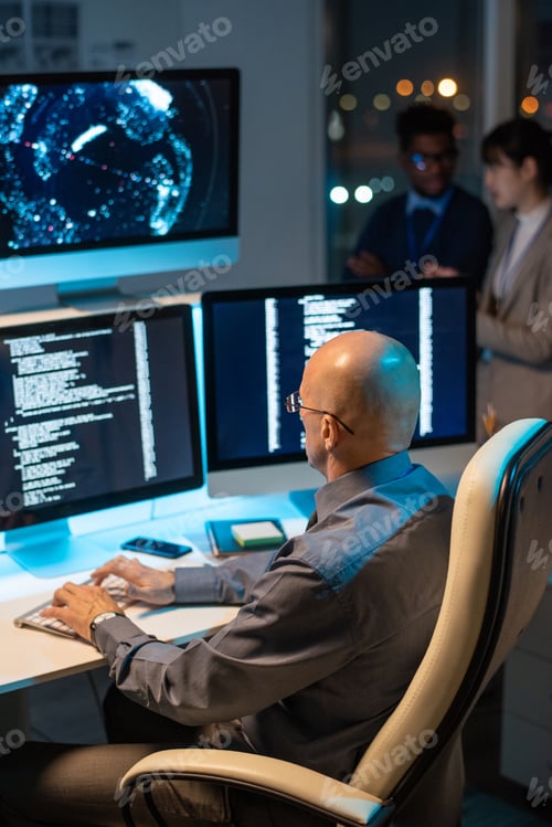 Preview: Bald mature businessman decoding data on computer screen