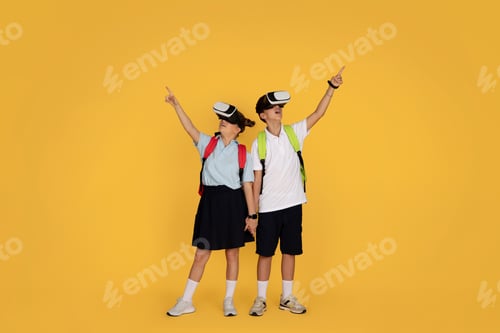 Preview: Happy surprised european teen pupil with backpacks, in vr glasses point fingers up at free space at