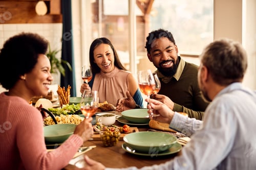 Preview: Happy black man having fun while talking with is friends during a meal at dining table.