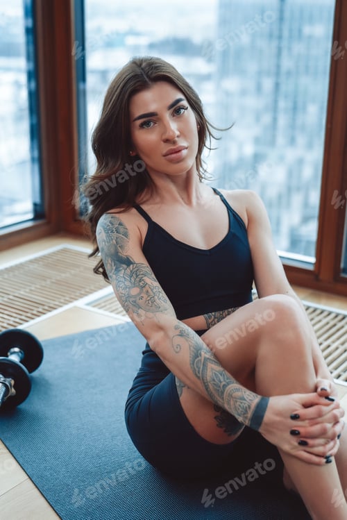 Preview: Portrait of skinny brunette girl in stylish sports clothes sitting and posing looking at camera.