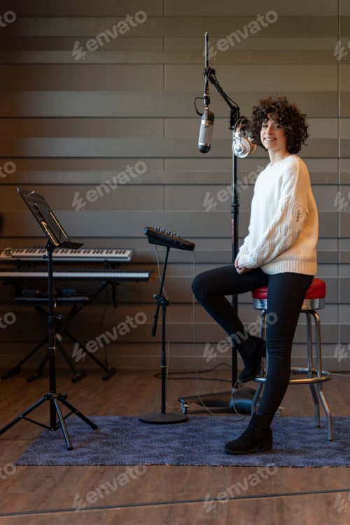 Preview: A young curly hair singer woman recording a song in a real studio. Vertical photo