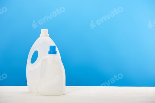 Preview: close-up view of plastic containers with laundry liquids on blue