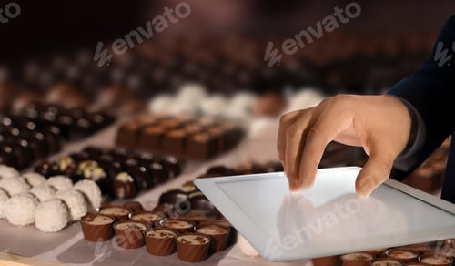 Preview: Production line of chocolate candies. Man working with tablet, closeup