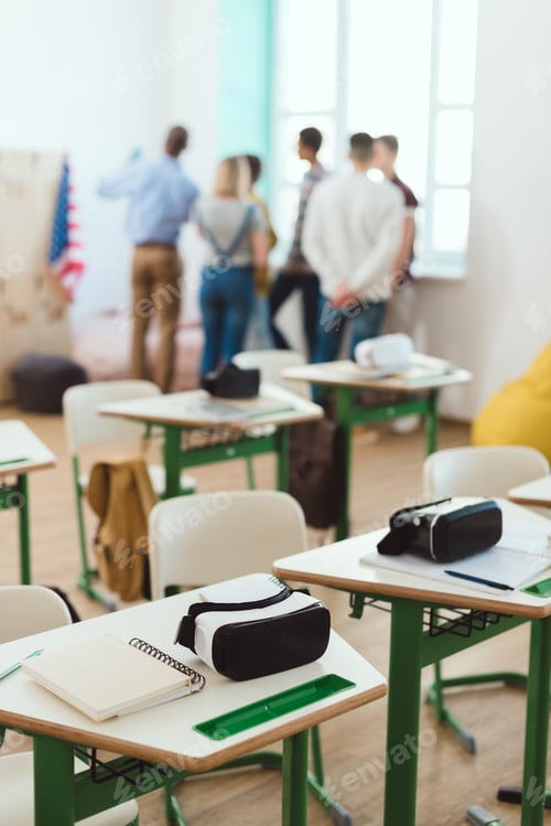 Preview: Virtual reality headsets on tables and teacher with schoolchildren standing behind