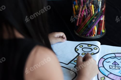 Preview: child is colouring a page in the book, view from behind