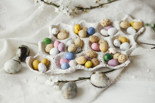 Preview: Stylish colorful easter eggs in tray and cherry blossoms on rustic table with linen cloth