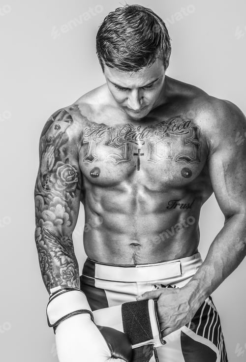 Preview: A muscled and tattooed man is putting on boxing gloves