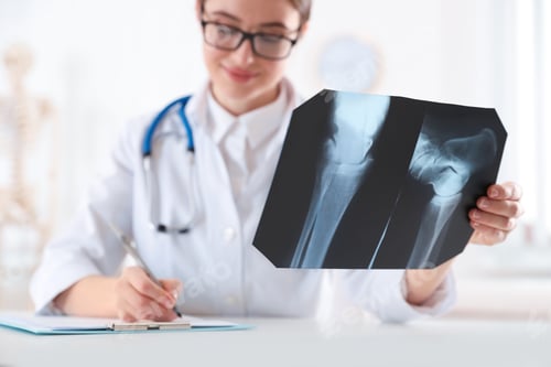 Preview: Orthopedist examining radiography at desk in office, focus on X-ray picture