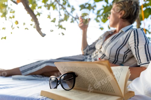 Preview: Woman reading book on swing bed in beach, Ginto island, Linapacan, Philippines