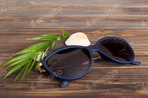 Preview: sunglasses with seashell lying on table background. Sunglasses
