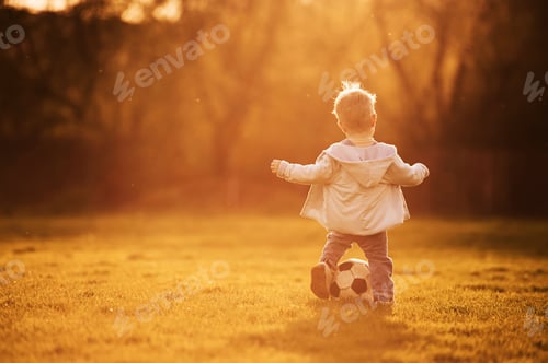 Vista previa: Playing with soccer ball. Cute happy little boy is on the field outdoors