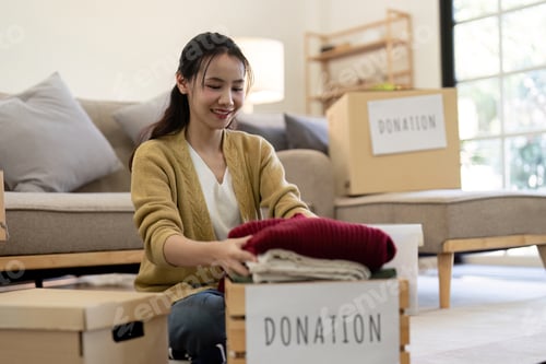 Preview: Woman asian holding donation box full with clothes and select clothes. Concept of donation and