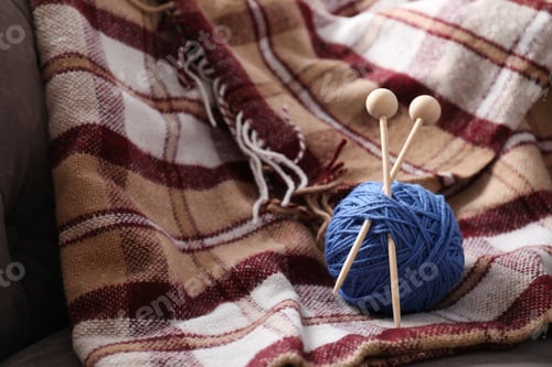 Preview: Ball of yarn with knitting needles on checkered plaid