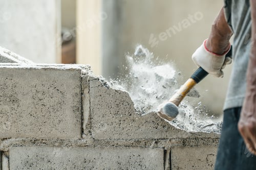 Preview: Hand of worker using hammer smashing and demolish on brick wall at construction site