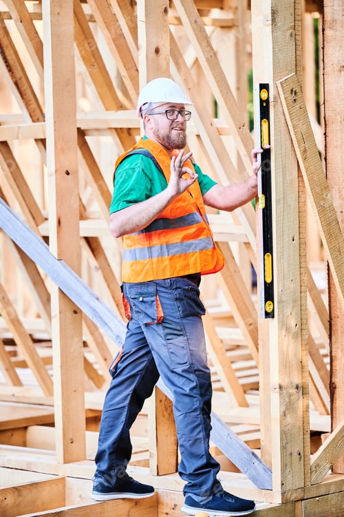Preview: Carpenter using spirit level while constructing wooden frame house.